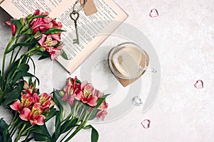 Alstroemeria flowers, a cup of coffee and a book on a light marble table