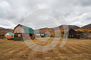Altai autumn farm. Wooden house on hill, wooden cabin. Haystacks in the yard, remote remote mountain village