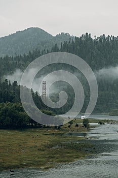 Altai nature at dawn in the fog. Haze in the forest and on the lake, atmospheric weather for the screensaver.