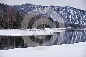 Altai river Biya in winter season. Banks of river are covered by ice and snow