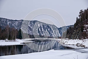 Altai river Biya in winter season. Banks of river are covered by ice and snow