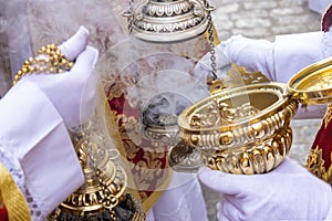 An altar boy or acolyte in a Holy Week procession filling one of the censers with incense