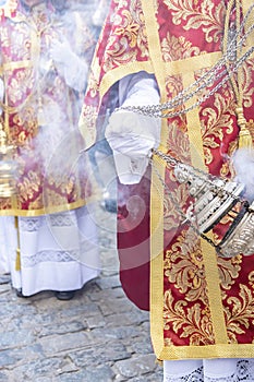 Altar boy or acolyte in the holy week procession shaking a censer to produce smoke and fragrance of incense