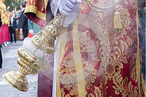 Altar boy or acolyte in the holy week procession shaking a censer to produce smoke and fragrance of incense