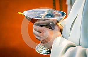 Altar boy is holding a boat filled with incense