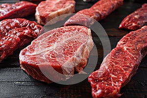 Alternative black angus cut top blade steak near denver steak close up in front of other cuts in butchery on old wood table side