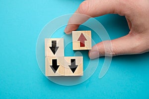 Alternative business development concept - hand holds wooden cube with red arrow