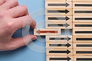 Alternative business development concept - hand holds wooden cube with red arrow on blue background