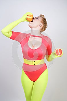 Alternative caucasian girl with short hair dressed in sporty red spandex bodysuit and bright tights with green neon gloves. curvac