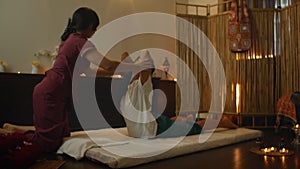 Alternative Chinese medicine, an Asian woman performs therapeutic massage on the back and legs of a Caucasian woman