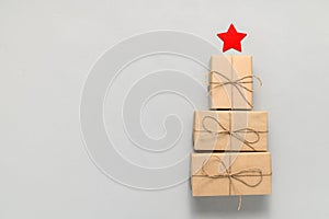 Alternative Christmas tree made from gift boxes with a red star on a light gray background.