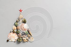 Alternative Christmas tree made from seashells and with a red starfish on a light gray background.