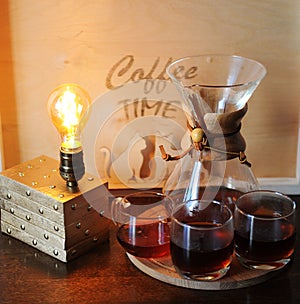 Alternative coffee brewing in the filter. Glass beakers. Table lamp with Edison bulb