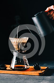 Alternative coffee brewing method, using pour over dripper and paper filter. Black background photo