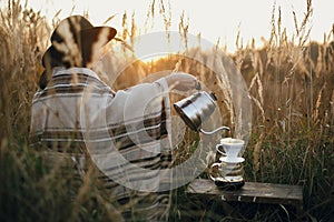 Alternative coffee brewing in travel. Hipster woman in hat pouring hot water into coffee in filter in pour over on glass flask on