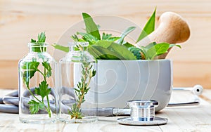 Alternative health care concept. Fresh herbs green mint ,rosemary ,parsley ,sage and lemon thyme in laboratory glassware with ste photo