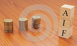 Alternative investment Funds or AIF on wooden block letters with Stack of currency coins.