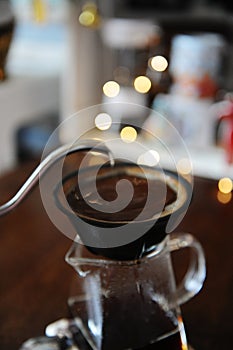 Alternative manual coffee brewing in porous ceramic paperless dripper filter. Gooseneck kettle. Blurry light background