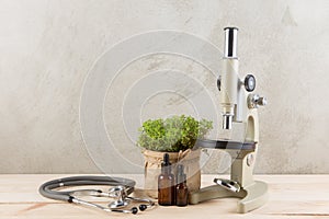 Alternative medicine and botany pharmaceutical bottles, medicinal herbs, microscope and stethoscope on a wooden table