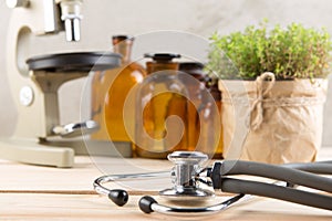 Alternative medicine and botany pharmaceutical bottles, medicinal herbs, microscope and stethoscope on a wooden table