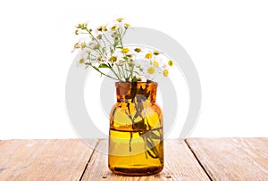 Alternative medicine concept - bottle with camomile on wooden ta