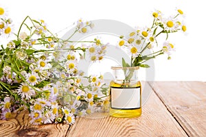 Alternative medicine concept - bottle with camomile on wooden ta