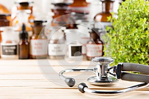 Alternative medicine concept medicine in bottles, medicinal herbs and stethoscope on a wooden table