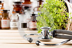 Alternative medicine concept medicine in bottles, medicinal herbs and stethoscope on a wooden table
