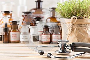 Alternative medicine concept medicine in bottles, medicinal herbs and stethoscope on a wooden table