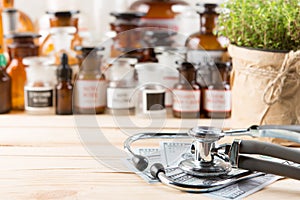 Alternative medicine concept medicine in bottles, medicinal herbs and stethoscope on a wooden table