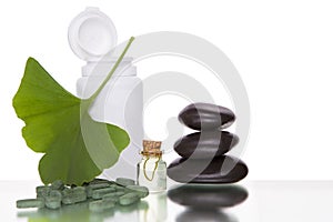 Alternative medicine - ginkgo leaves and tablets n a bottle. Isolated over white background photo