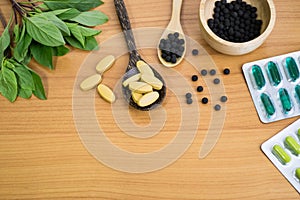 Alternative medicine, herbal pills, tablets , blisters of capsules on wood background