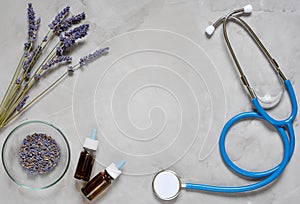 Alternative medicine herbs of lavender, oil and stethoscope on grey background