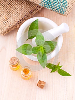 Alternative medicine lemon basil oil natural spas ingredients for aroma aromatherapy with mortar on wooden background.