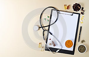 Alternative medicine, nathuropathy or ayurveda concept. Blank clipboard with stethoscope, various healing herbs, spices, capsules