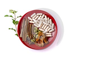 Alternative medicine system of Ayurveda with cinnamon, cloves, cardamom, javitri and green tulsi leaf in a red plate on white