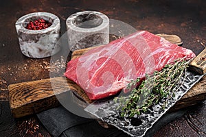 Alternative raw flap flank beef meat steak on butcher board. Dark background. Top view