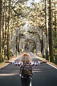 Alternative travel concept with curly hipster woman viewed from back open his arms and feel the freedom of the outdoors nature