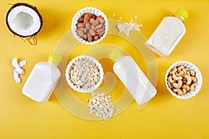 Alternative types of vegan milks in bottles on a yellow background, Various vegan plant based milk and ingredients, non-dairy milk