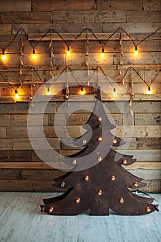 Alternative wooden christmas tree. A handmade New Year tree with light bulb on the floor on wooden background. Loft