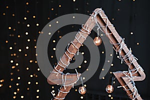 Alternative wooden christmas tree. A handmade New Year tree with light bulb on garland lights black background. Lifestyle trend.