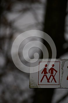 Altes Wanderweg Schild mit roten Figuren und unscharfem Hintergrund