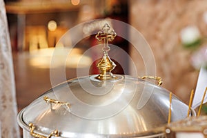 Aluminium church font, large bowl, with golden cross and saint water for the baptism of babies in Orthodox Church temple