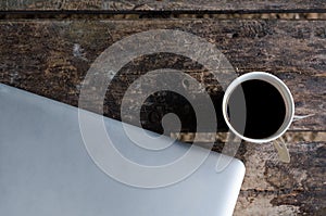 Aluminium Notebook (laptop) with cup of hot coffee on wood table.