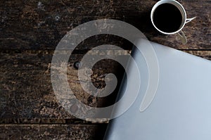 Aluminium Notebook (laptop) with cup of hot coffee on wood table.