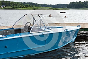 Aluminum blue fishing boat with a motor near the lake shore, fishing, active recreation, Background of nature