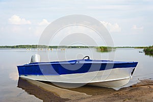 Aluminum blue fishing boat with a motor near the lake shore, fishing, tourism, active recreation, lifestyle