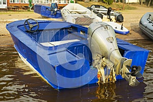 Aluminum blue fishing boat with a motor near the lake shore, fishing, tourism, active recreation, lifestyle. Background of nature