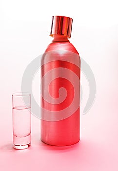 Aluminum bottle and a glass of vodka in pink light