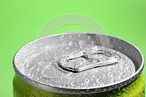 Aluminum can of beverage covered th water drops on green background, closeup